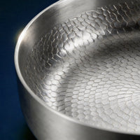 Close-up van de gehamerde binnenkant en de hoge rand van de titanium pan