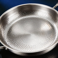 Close-up van de gehamerde bodem van de titanium pan met twee handgrepen