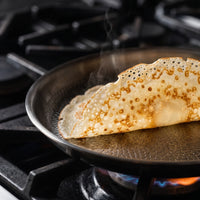 Dubbelgevouwen crêpe in de titanium crêpepan op een gasfornuis