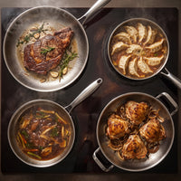 De titanium familieset van bovenaf op een kookplaat, met steak, dumplings, een stoofgerecht en kippendijen