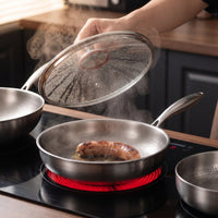 Hand tilt de beslagen glazen deksel van een titanium pan met braadworst op een kookplaat