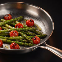 Groene asperges en geroosterde cherrytomaten in de titanium koekenpan