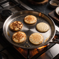 Vijf kleine pannenkoekjes in de titanium crêpepan op een gasfornuis