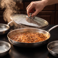 Hand tilt de beslagen glazen deksel van een titanium koekenpan met pruttelende saus